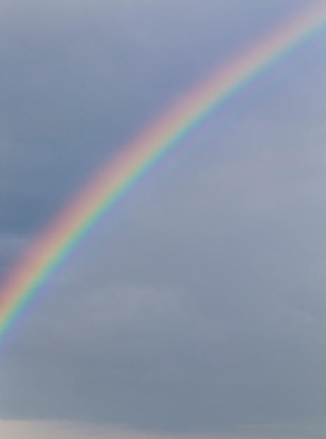 Gekleurde regenboog tegen een bewolkte stormachtige lucht en regen, landschap, weinig scherptediepte, foto is niet in focus als achtergrond