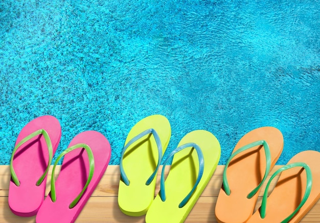 Foto gekleurde slippers op de rand van een zwembad.