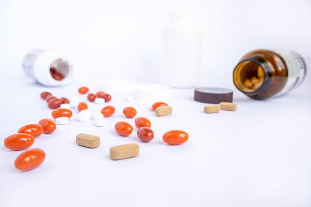Gekleurde vitaminen naast plastic en bruine glazen pot op witte achtergrond