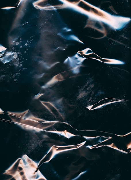 Foto gekneusde textuur oude folie zwarte gerimpelde gerimpelde plastic overlay met metallisch effect gekleurd papier versleten