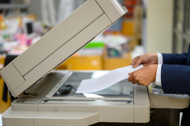 Geknipte hand van een zakenvrouw die een kopieermachine op kantoor gebruikt