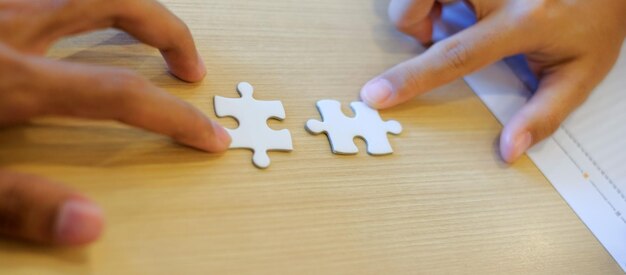 Foto geknipte handen spelen met puzzelstukken op tafel