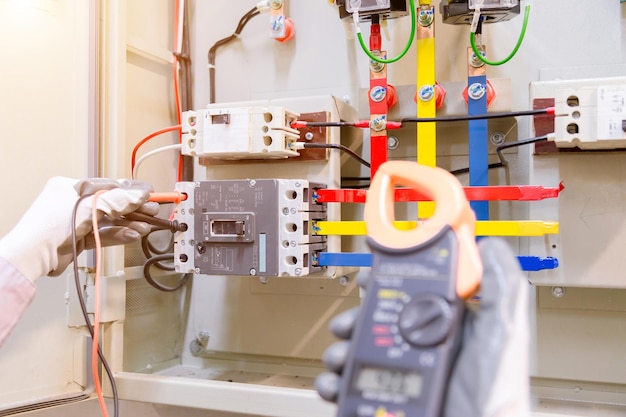 Foto geknipte handen van een elektricien die het schakelkastje in een fabriek controleert