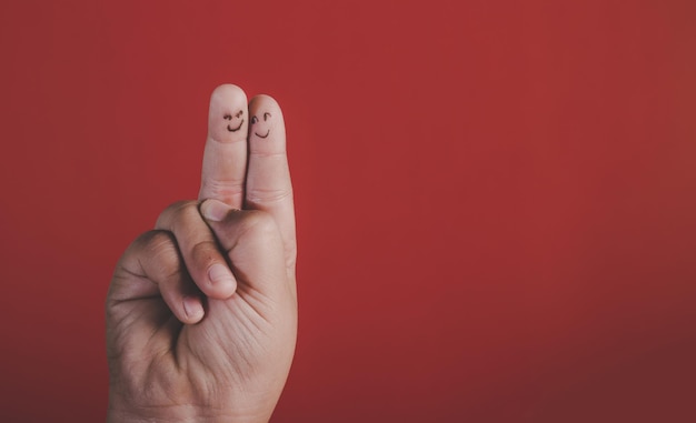 Foto geknipte vingers met antropomorfe gezichten met een vredesteken op een rode achtergrond