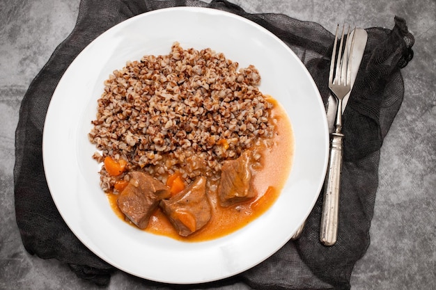 Gekookt boekweit met vlees en saus op witte schotel