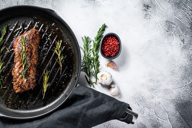 Gekookt bovenmes, Denver steak in een pan. Marmer vlees rundvlees. Grijze achtergrond