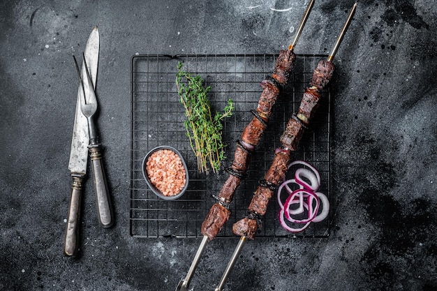 Gekookt op de grill beef shish kebab met groenten en kruiden gegrild vlees Zwarte achtergrond Bovenaanzicht