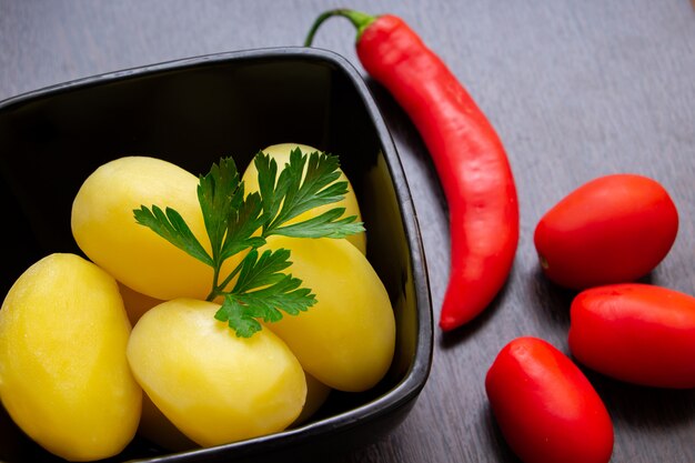 Gekookte aardappelen met chilipepers en tomaten op een donkere achtergrond