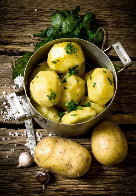 Gekookte aardappelen met kruiden en zout op een houten tafel.