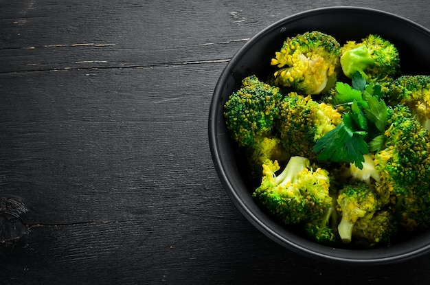 Foto gekookte broccoli in een zwarte plaat op een zwarte achtergrond bovenaanzicht vrije ruimte voor uw tekst