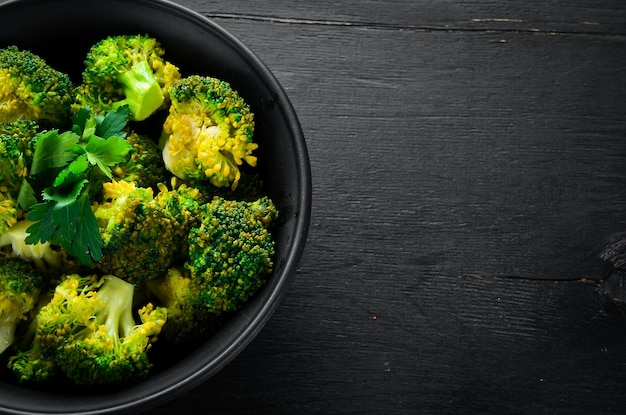 Foto gekookte broccoli in een zwarte plaat op een zwarte achtergrond bovenaanzicht vrije ruimte voor uw tekst