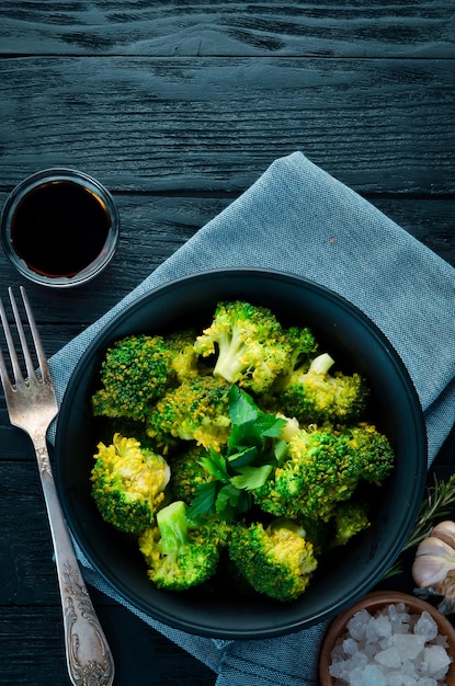 Gekookte broccoli in een zwarte plaat Op een zwarte achtergrond Bovenaanzicht Vrije ruimte voor uw tekst