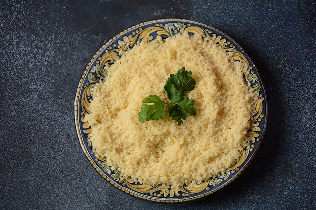 Gekookte couscous met groene peterselie in keramische plaat