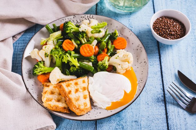 Foto gekookte eieren broccoli bloemkool groene bonen en wortels op een bord op tafel