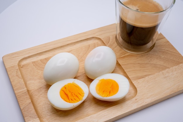 Gekookte eieren met zwarte koffie voor ontbijt op houten dienblad