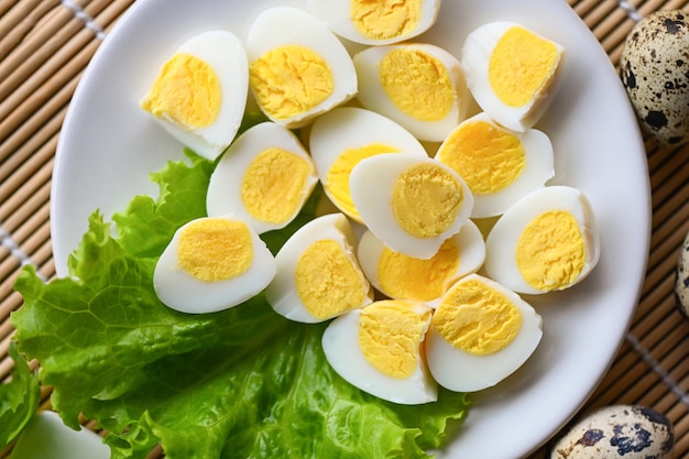 Gekookte eieren voedsel kwarteleitjes op witte plaat ontbijteieren met verse kwarteleitjes en groentesla salade op houten tafel achtergrond