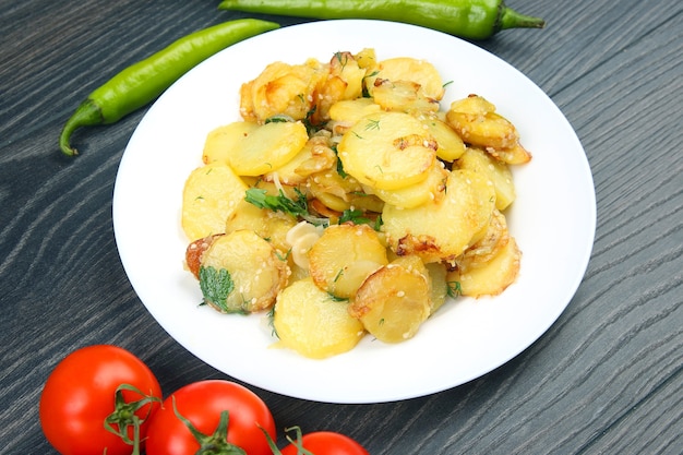 Gekookte gebakken aardappelen met kruiden en groenten in een plaat op een houten tafel