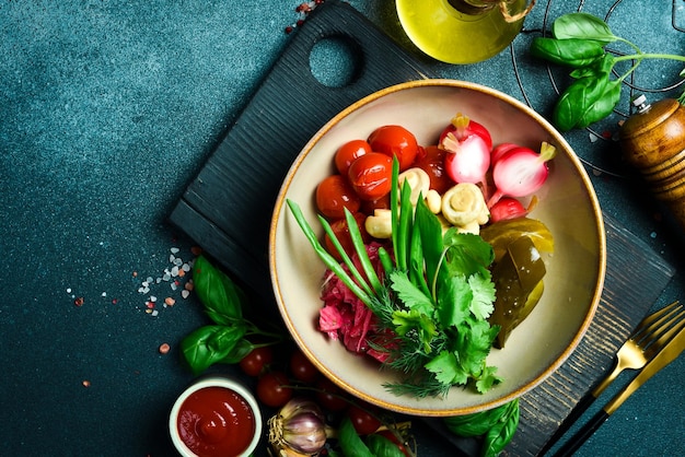 Gekookte groenten kool komkommer tomaten dichtbij op een bord op een zwarte stenen achtergrond