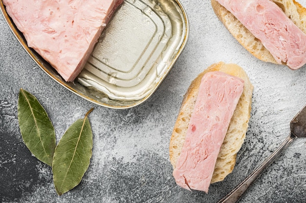 Gekookte ham uit het blikbrood sandwich op grijze stenen tafel achtergrond bovenaanzicht plat lag