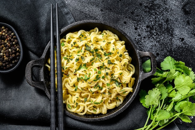 Gekookte instantnoedels met sojavlees in een pot. Vegetarisch gerecht. Zwarte achtergrond. Bovenaanzicht.