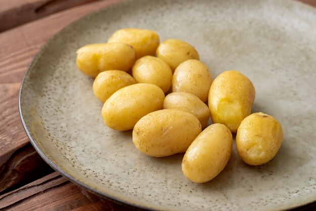 Gekookte jonge kleine aardappelen op een bord op een houten ondergrond.