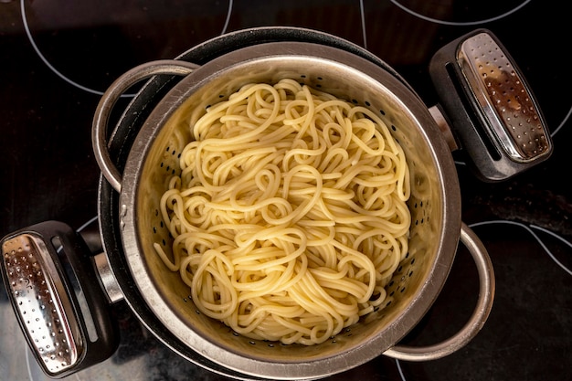 Gekookte kant-en-klare spaghetti gooien in een vergiet-aanzicht van bovenaf