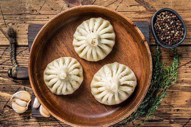 Gekookte khinkali dumplings met schapenvlees lamsvlees in houten plaat. houten achtergrond. bovenaanzicht.