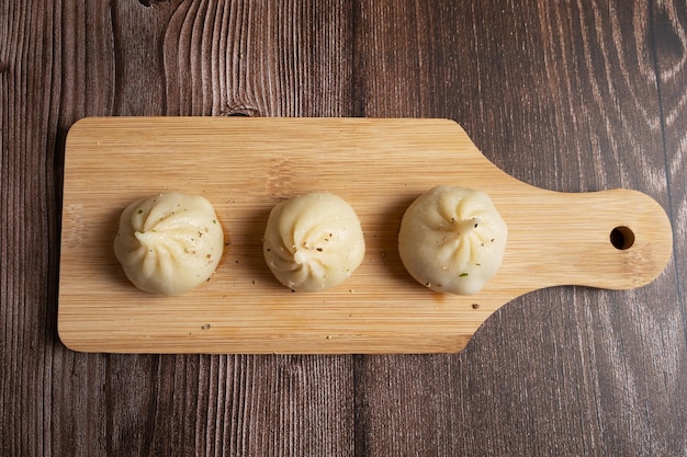 Gekookte khinkali op een houten bord en een houten achtergrond