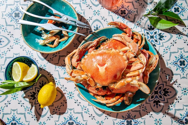 Gekookte krab op blauw bord citroenen rose wijn op tafel zonlicht immitatie