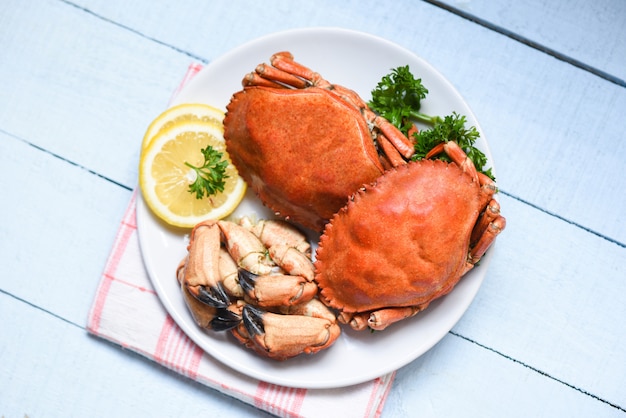 Gekookte krab op witte plaat en houten Zeevruchten gekookte rode steenkrabklauw met kruid en kruiden