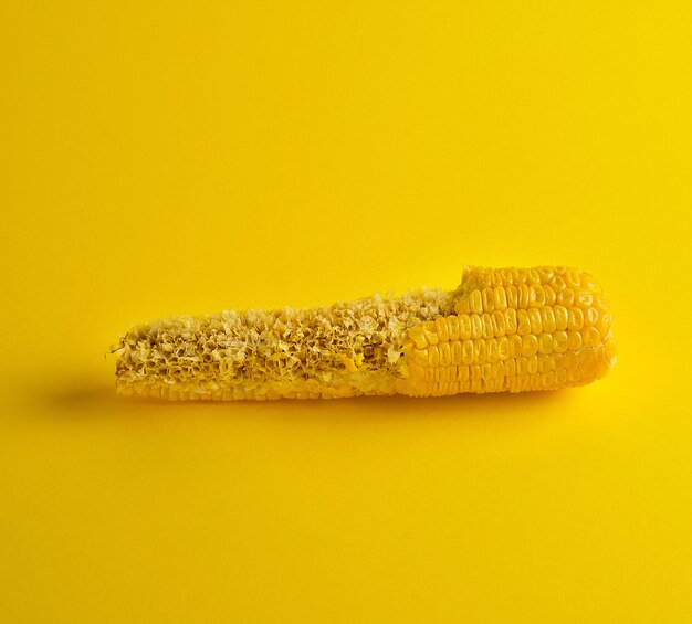 Gekookte maïskolf is gebeten en ligt op een geel