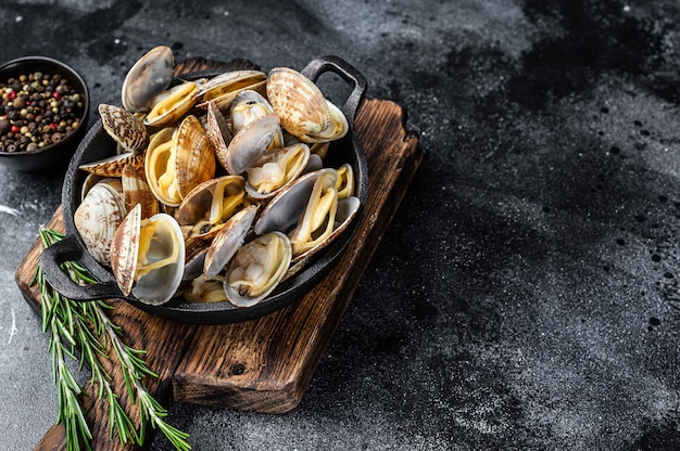 Gekookte mosselen vongole in een pan. Zwarte achtergrond. Bovenaanzicht. Ruimte kopiëren.