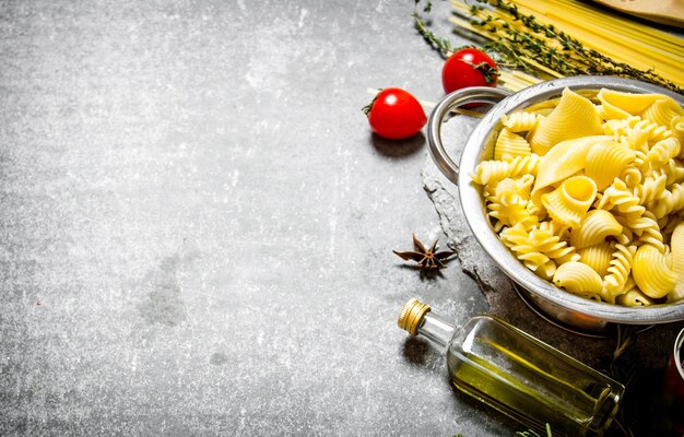 Gekookte pasta in de pan met olijfolie en tomaten op de stenen tafel