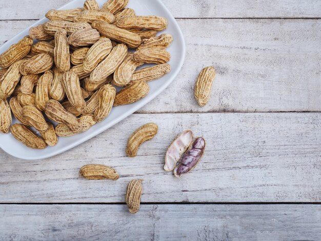 Gekookte pinda&#39;s op plaat over houten tafel.