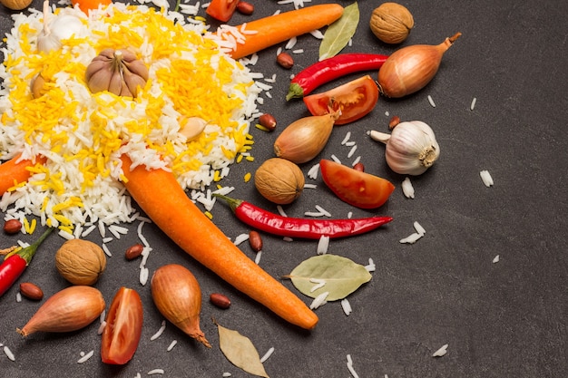 Gekookte rijst met knoflook. wortelen, uien, noten en tomaten op tafel. plat leggen