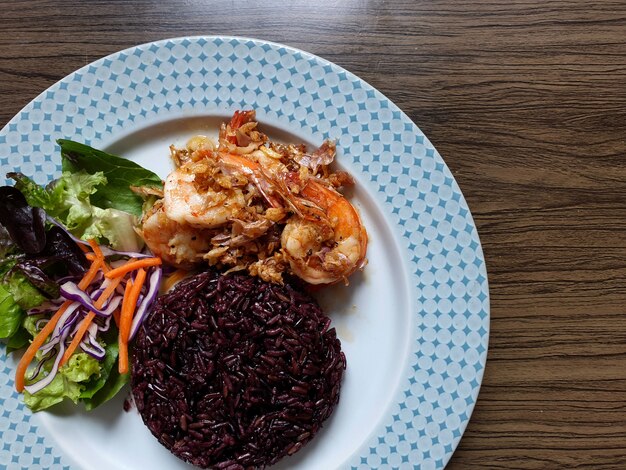 Gekookte rijstbes en gebakken garnalen met knoflook en peper gemengde salade in een bord