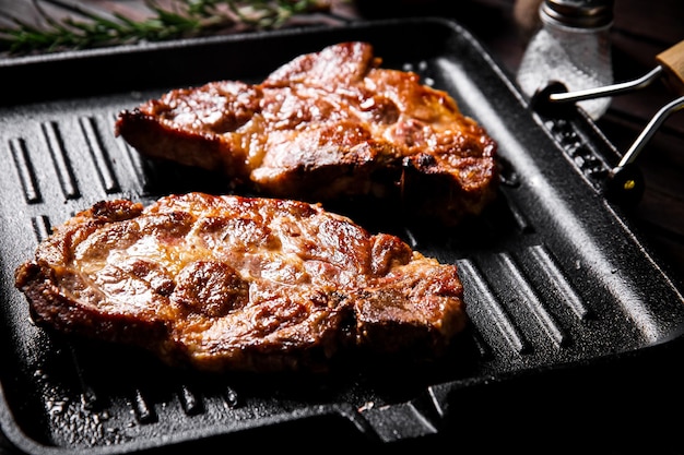 Gekookte varkenssteak in een koekenpan gegrild met rozemarijn