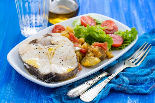 Gekookte vis met salade op witte schotel