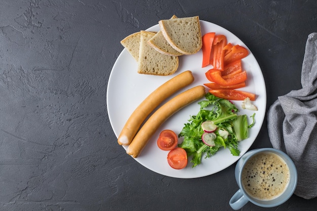 Gekookte worstjes met sla, tomaat, paprika en brood op een witte plaat bovenaanzicht ruimte voor tekst