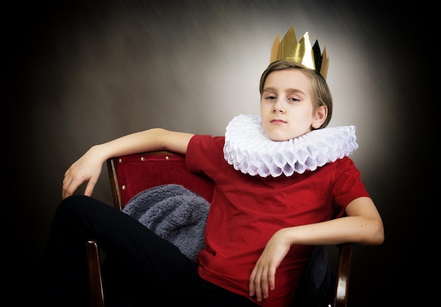 Foto gekroonde jongen zittend in een fauteuil