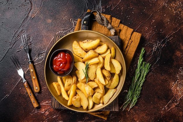 Gekruide aardappelpartjes met rozemarijn en tomatensaus in een bord Donkere achtergrond Bovenaanzicht