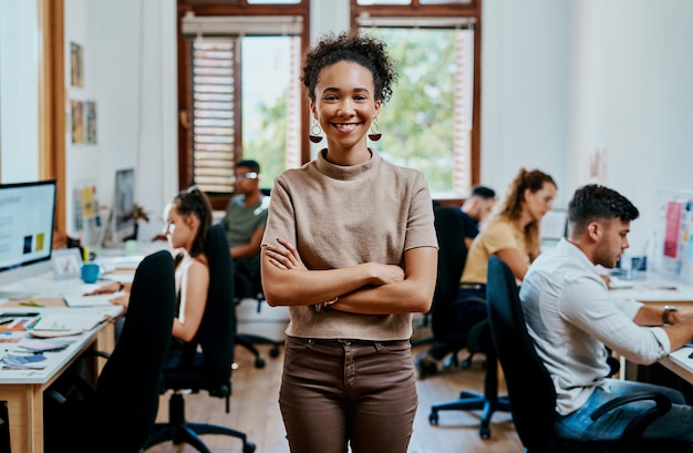 Gekruiste armen gelukkig en portret van vrouw in kantoor met trots voor management creativiteit of carrière Team zelfverzekerd en jonge vrouwelijke public relations werknemer met glimlach bij start-up agentschap in Spanje