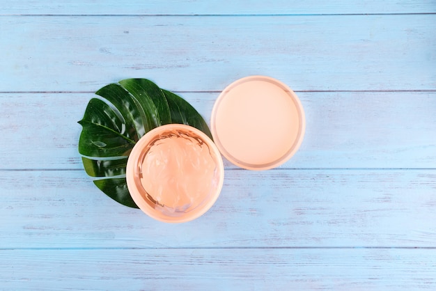 Gel serum of snail collagen in jar on blue wooden background. 