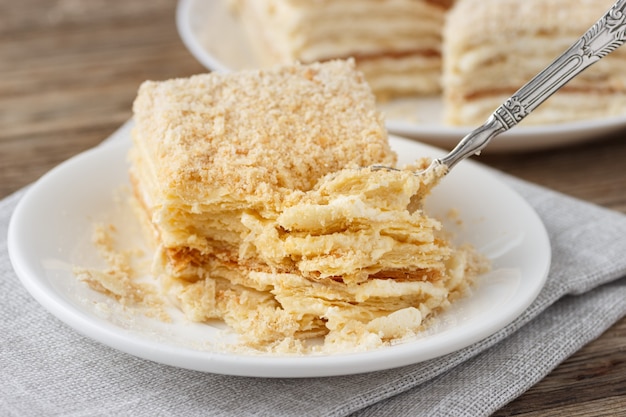 Foto gelaagde cake met crème napoleon millefeuille vanille schijfje op een witte plaat.