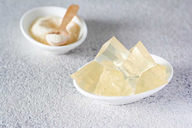 灰色の背景上のゼラチン、寒天、ゼラチン状の塊（結晶の形の立方体）。食品・製菓用ゲル化剤（コラーゲン）。