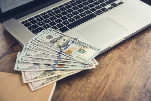 Geld, Amerikaanse dollarbiljetten, op laptopcomputer aan werktafel