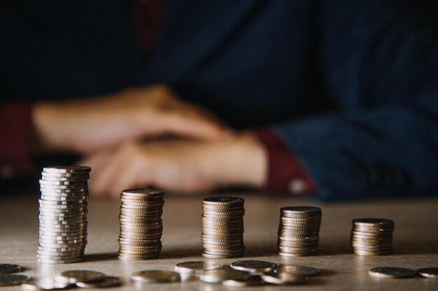 Geld besparen hand munten op stapel op tafel zetten met zonneschijn concept financiën en boekhouding