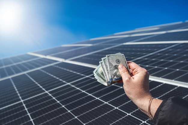 Geld besparen met zonne-energie en zonnepanelen Hand met dollars voor panelen het concept van elektriciteitsbesparing