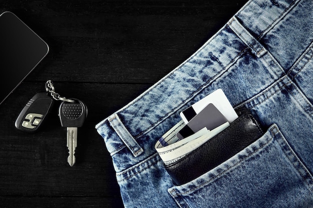 Geld debetkaart en creditcard zijn in de zak van blue jean autosleutels slim op houten achtergrond met...