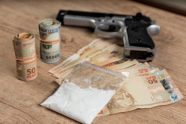 Geld, drugs en een pistool op een houten tafel